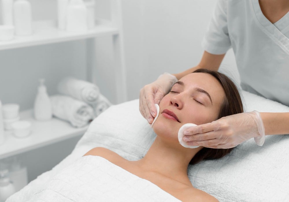 A person lies on a treatment couch cleansing skin in a clinic setting for a laser resurfacing procedure. 