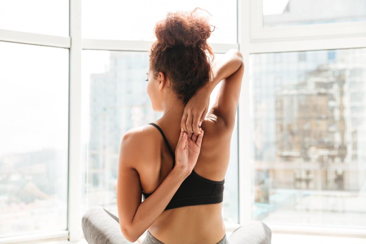 Young gym goer woman feeling less stiff in neck after receiving trapezius slimming injection treatments.