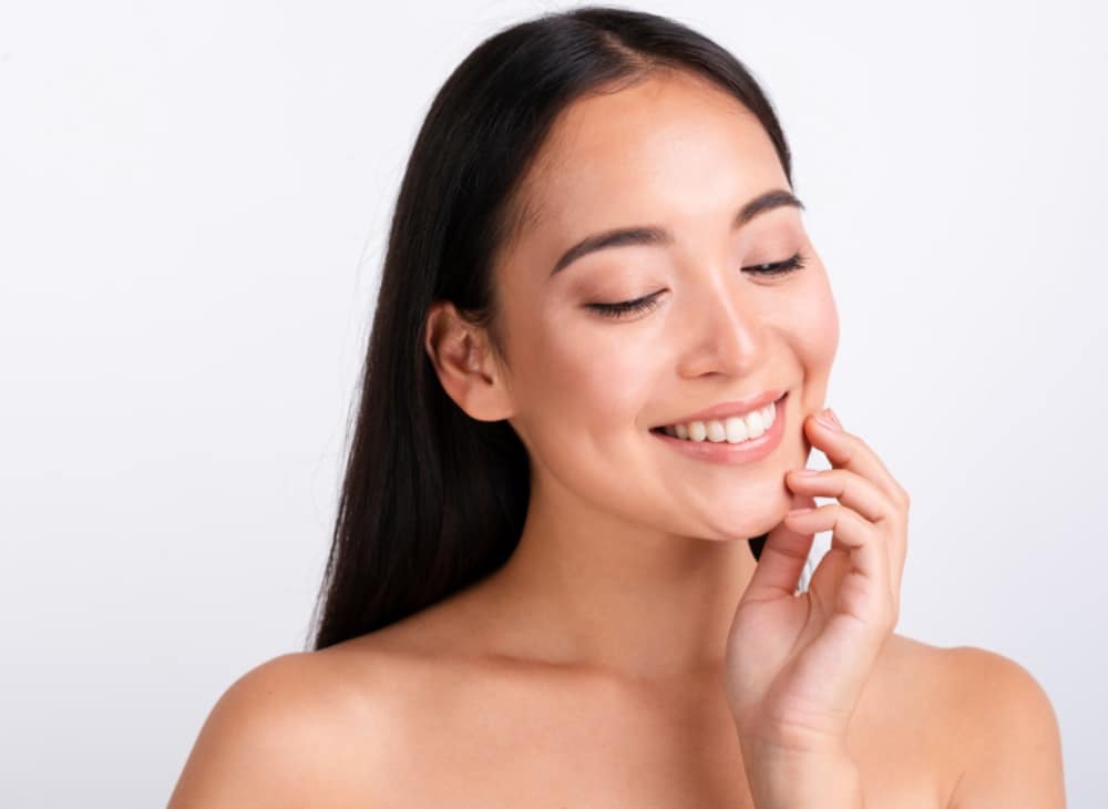A young woman with long dark hair smiles, with reduced wrinkles and fine lines after laser skin resurfacing procedure. 