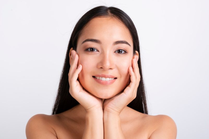 image of asian woman with hands on face, skincare, flawless skin