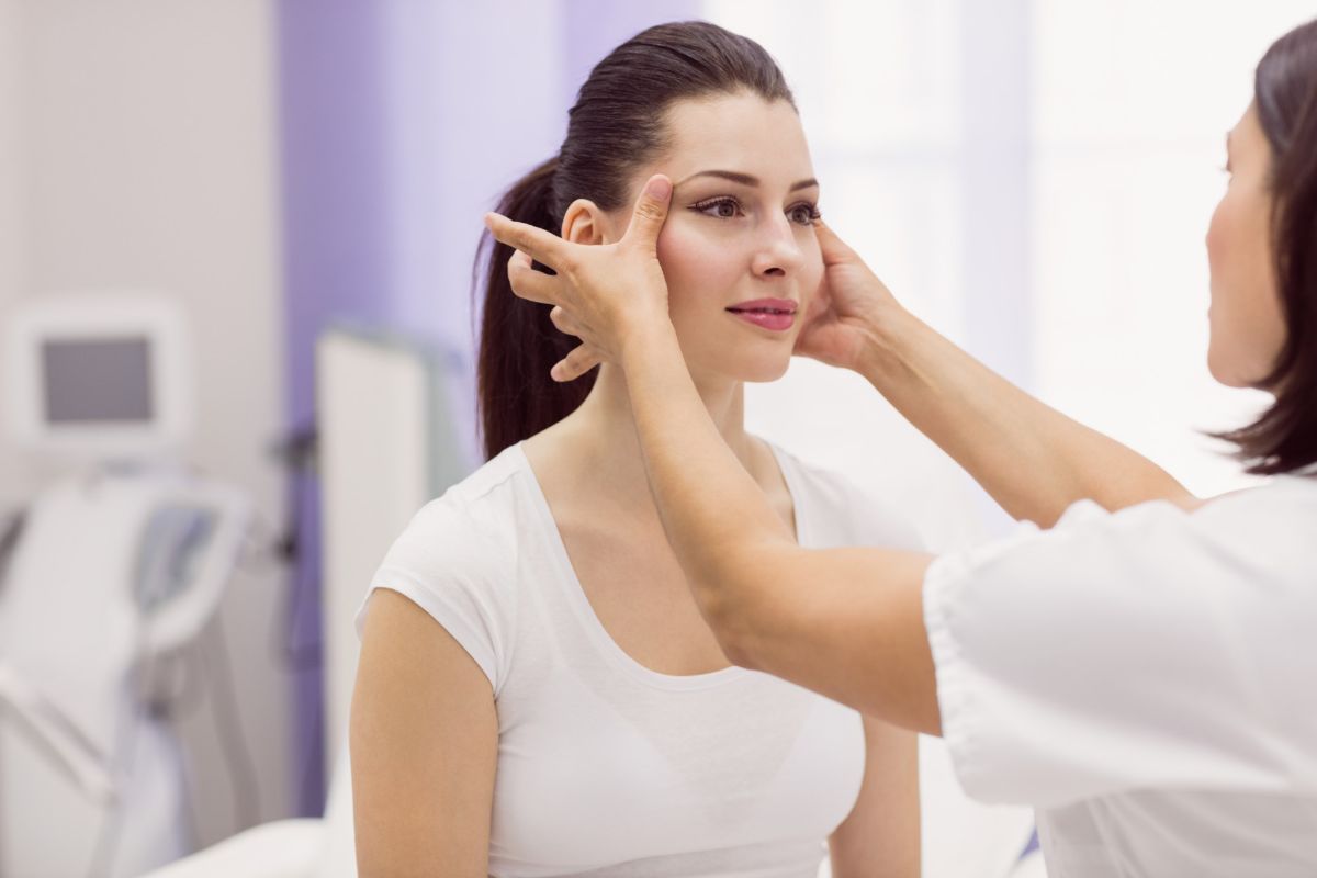 A cosmetic doctor examining female patient skin to treat saggy skin and wrinkles