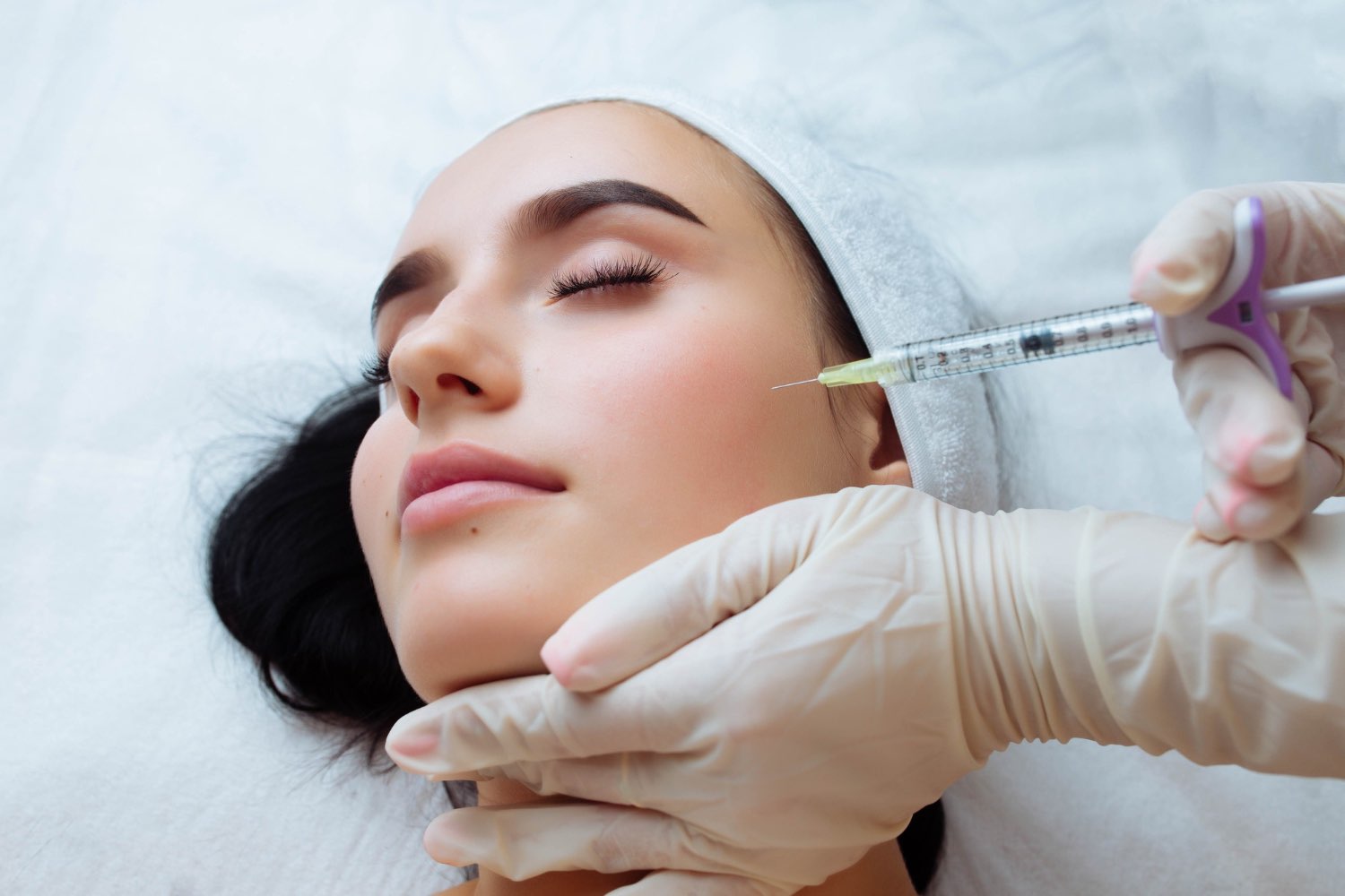 A cosmetic doctor inject fillers in a woman's skin to boost collagen