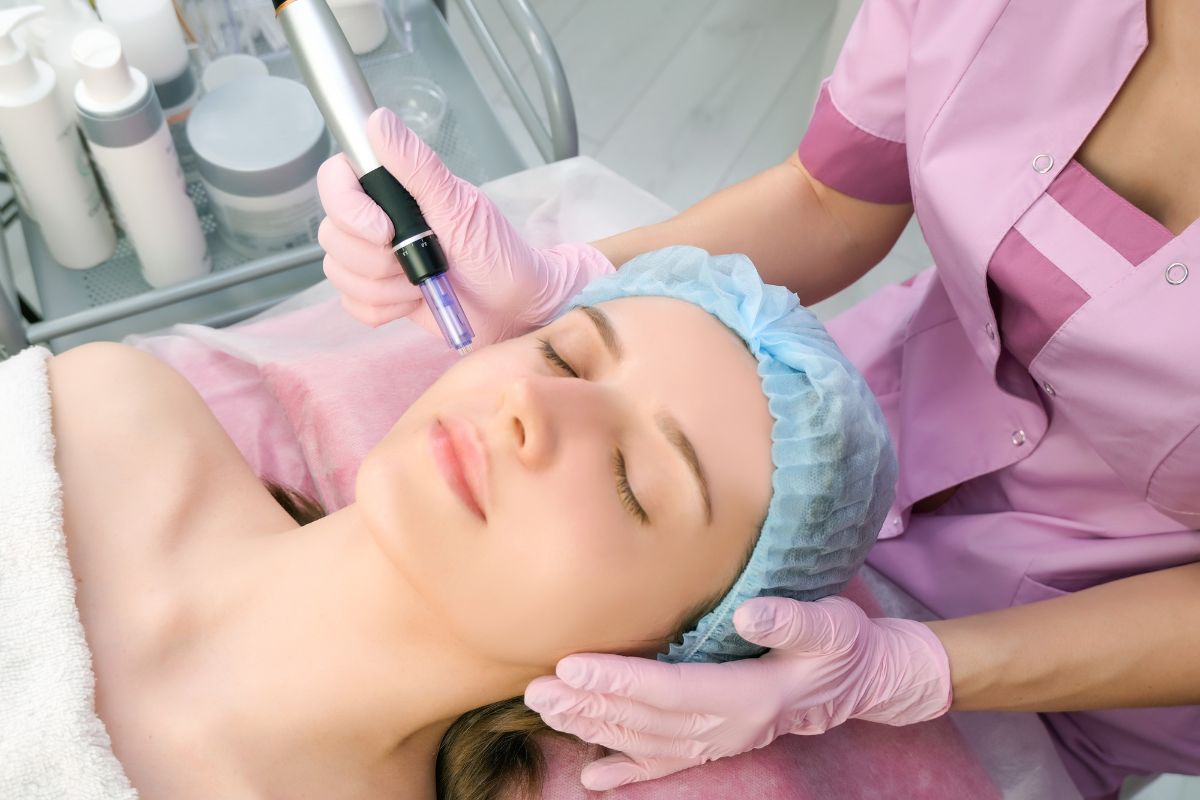 cosmetologist performs microneedling on a womans face
