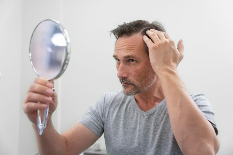 a middle aged man getting hair loss treatment looking at his hair in the mirror